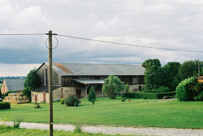 A field with a house and a barn in the background
